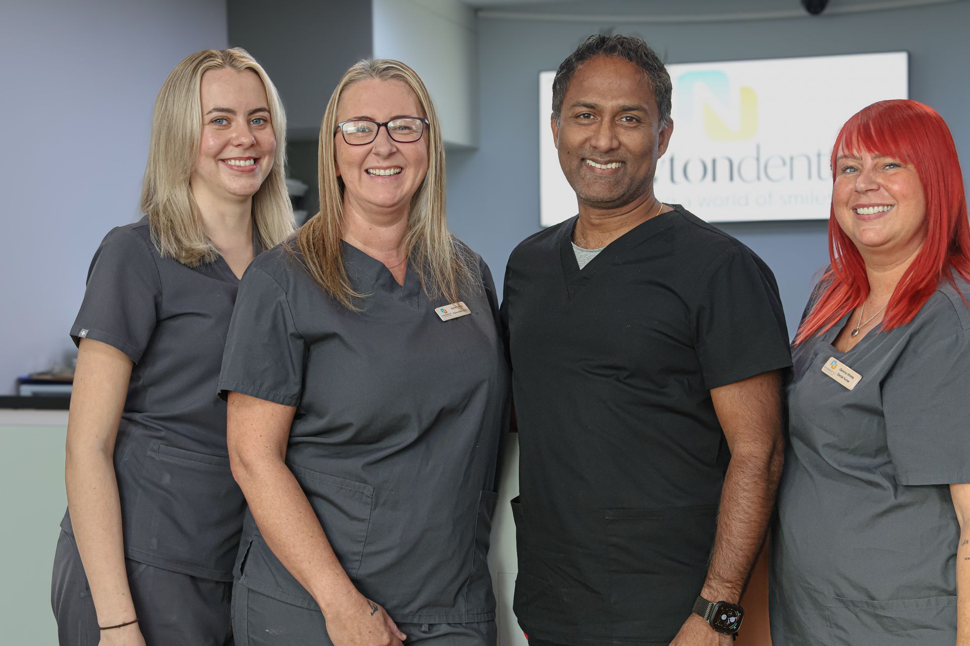 A man and two women are posing for a picture together. Dental professionals 