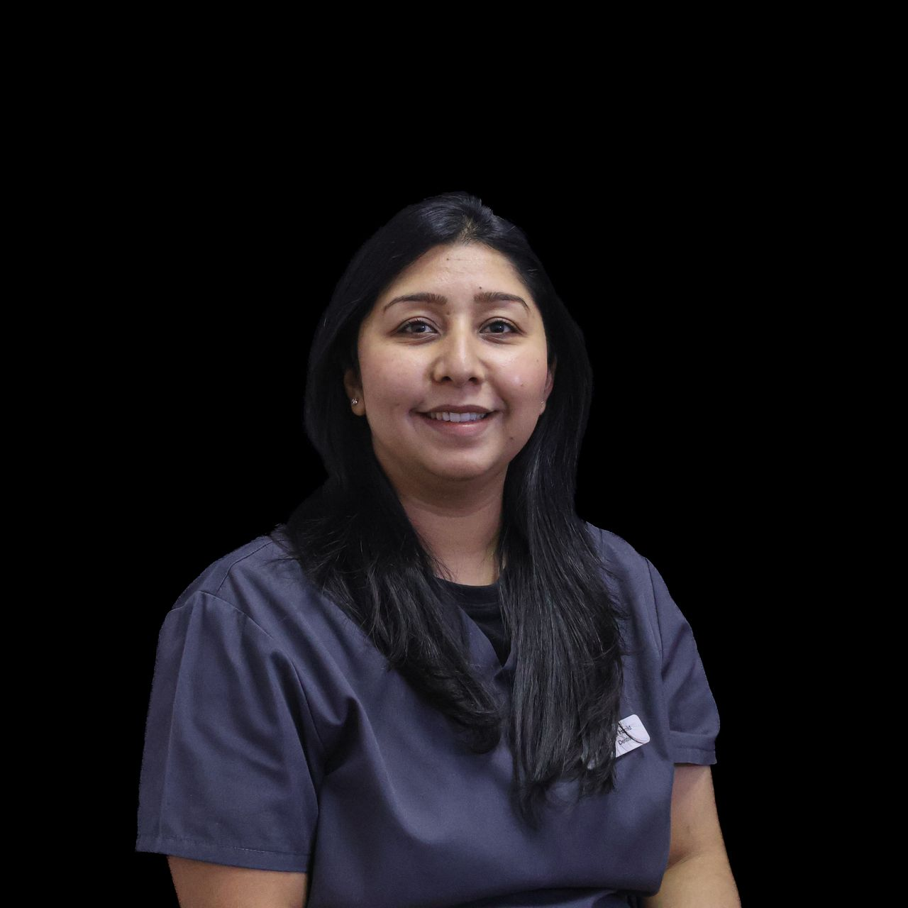 A woman in a grey scrub top is smiling for the camera.