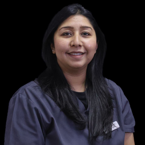 A woman in a grey scrub top is smiling for the camera.