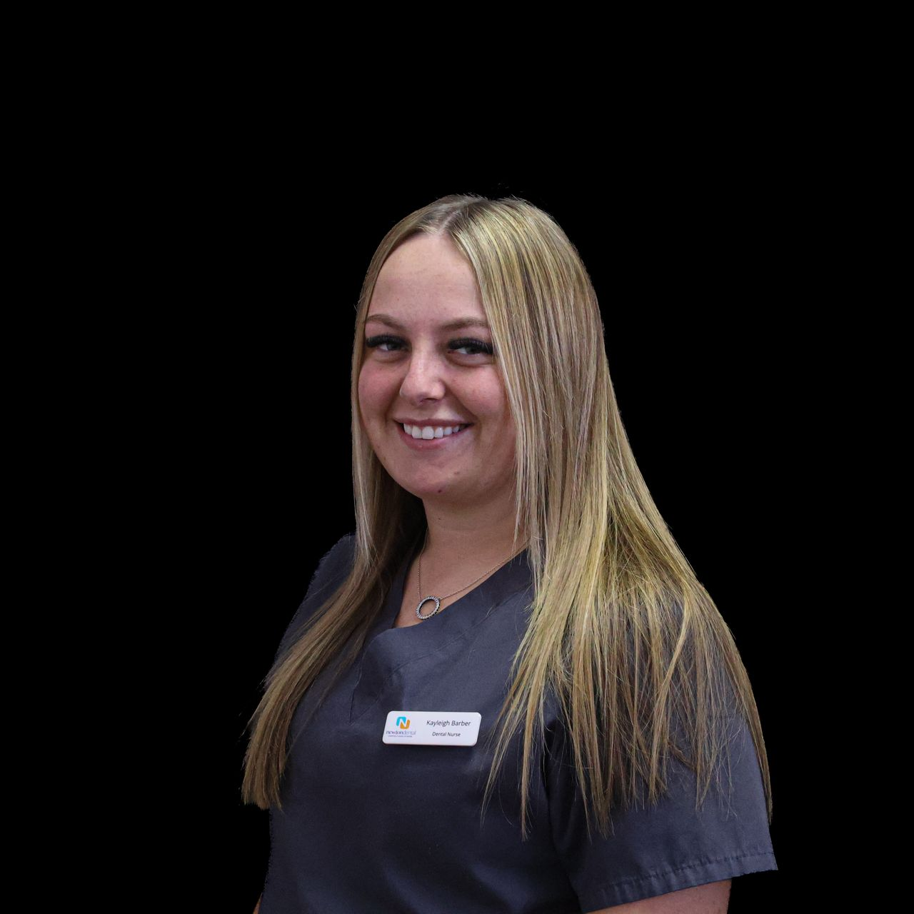 A woman in a gray scrub top is smiling for the camera.