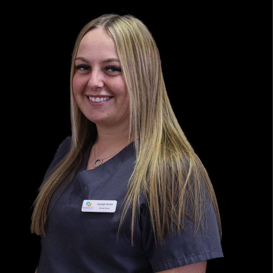 A woman in a gray scrub top is smiling for the camera.