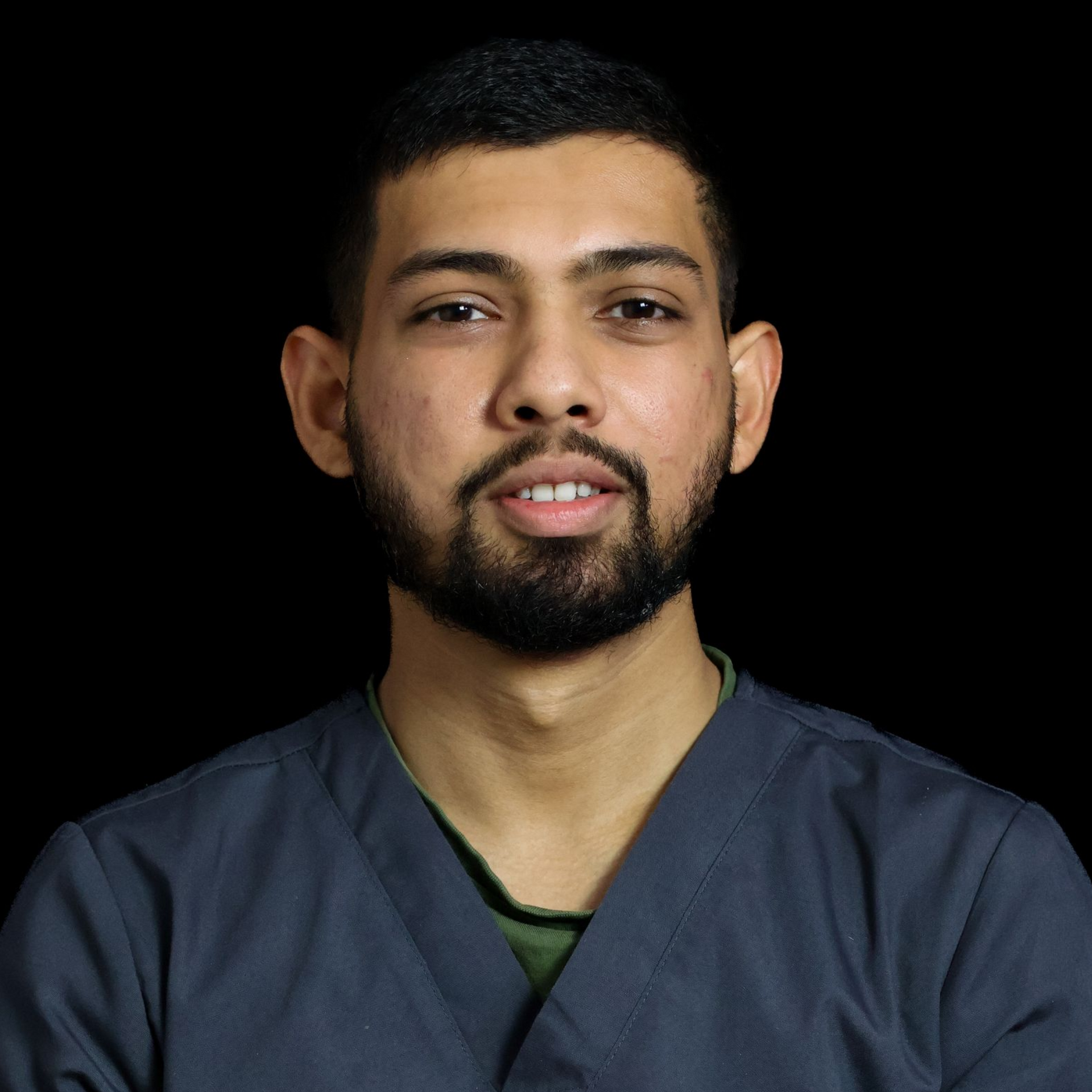 A man with a beard is wearing a scrub top and a black shirt.