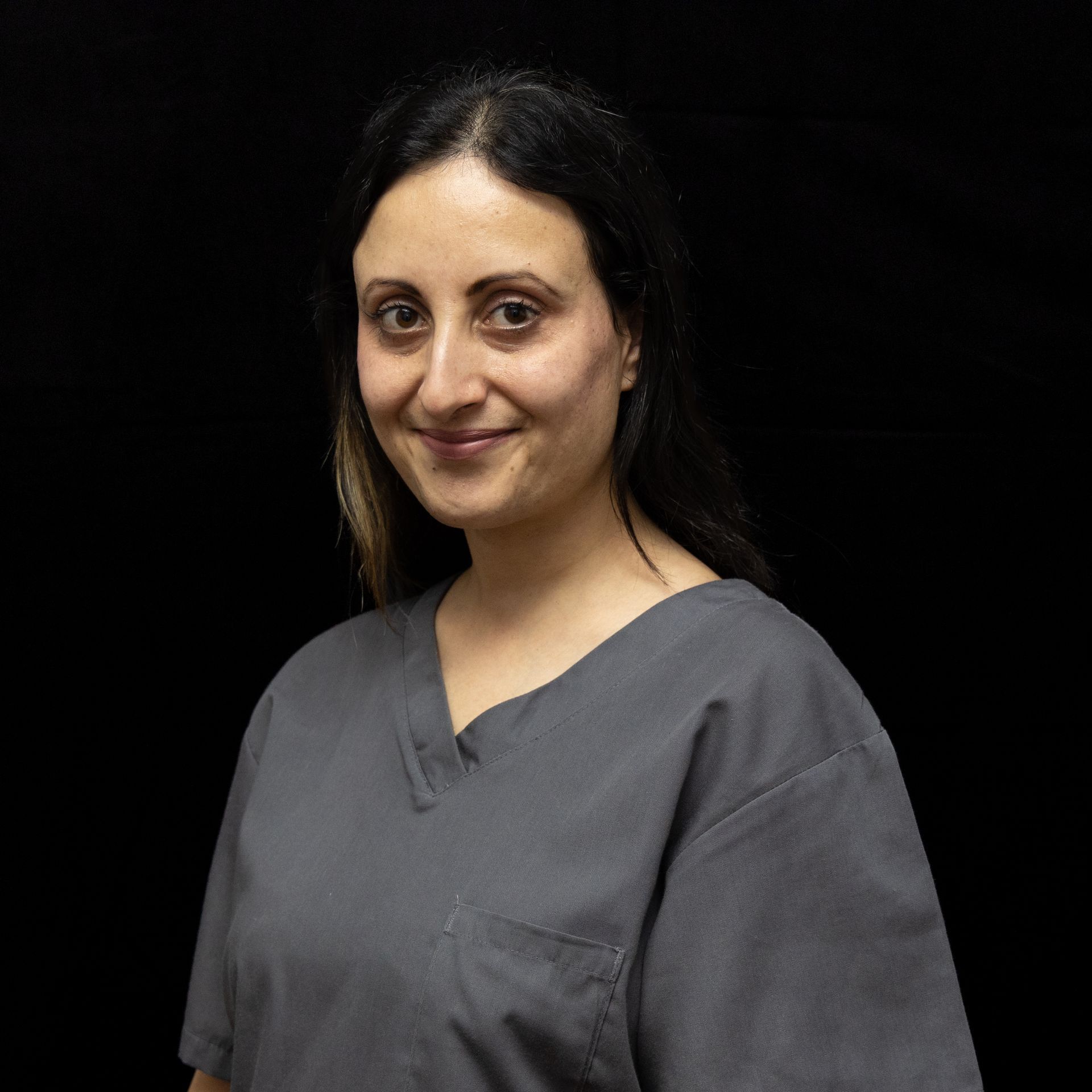 A woman in a grey scrub top is smiling for the camera.