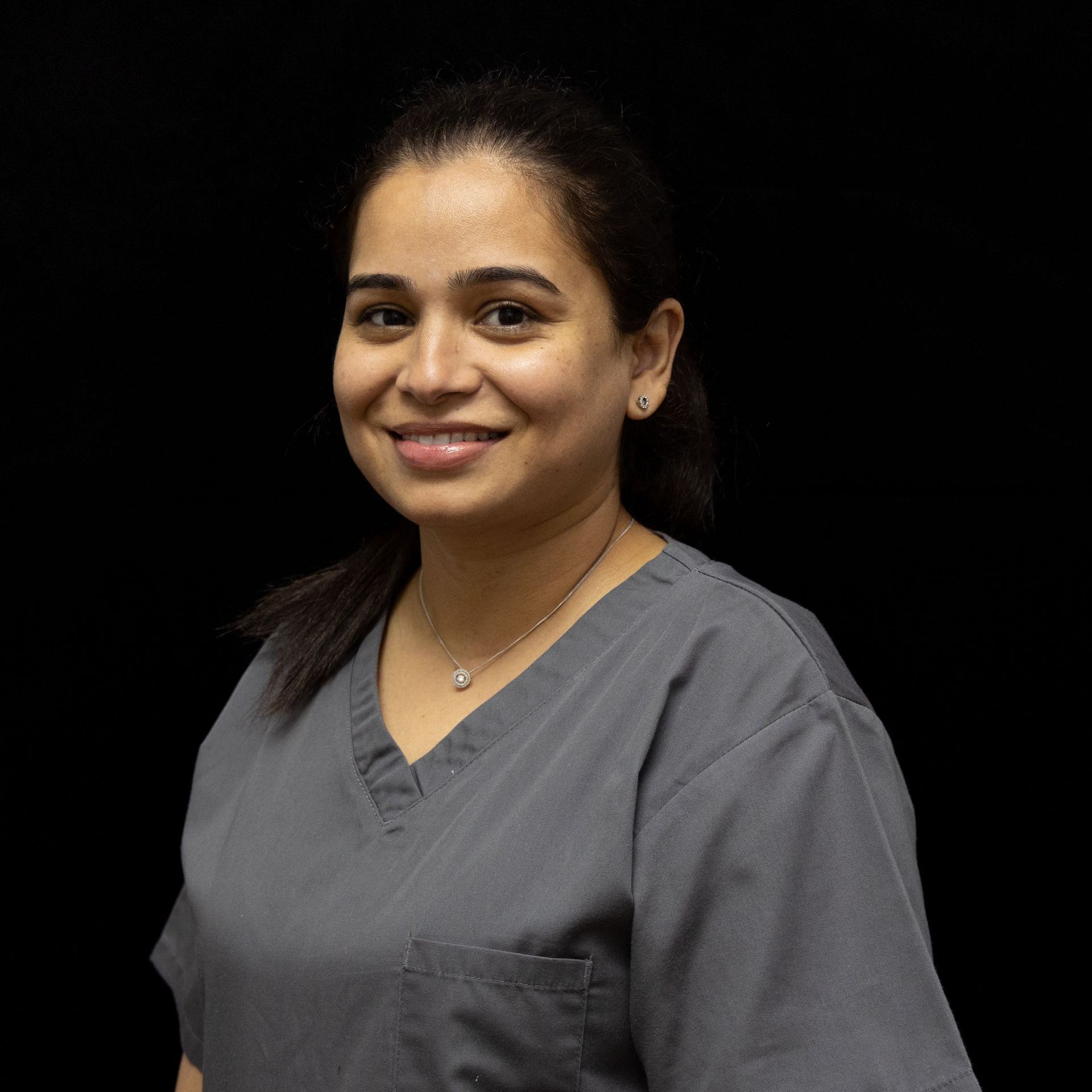 A woman in a grey scrub top is smiling for the camera.