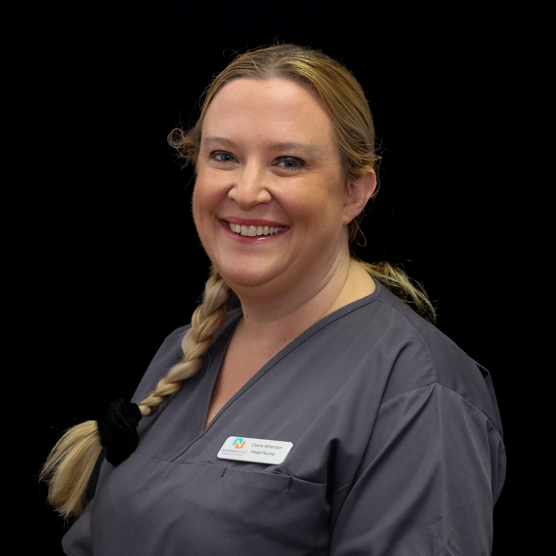 A woman in a gray scrub top is smiling for the camera.