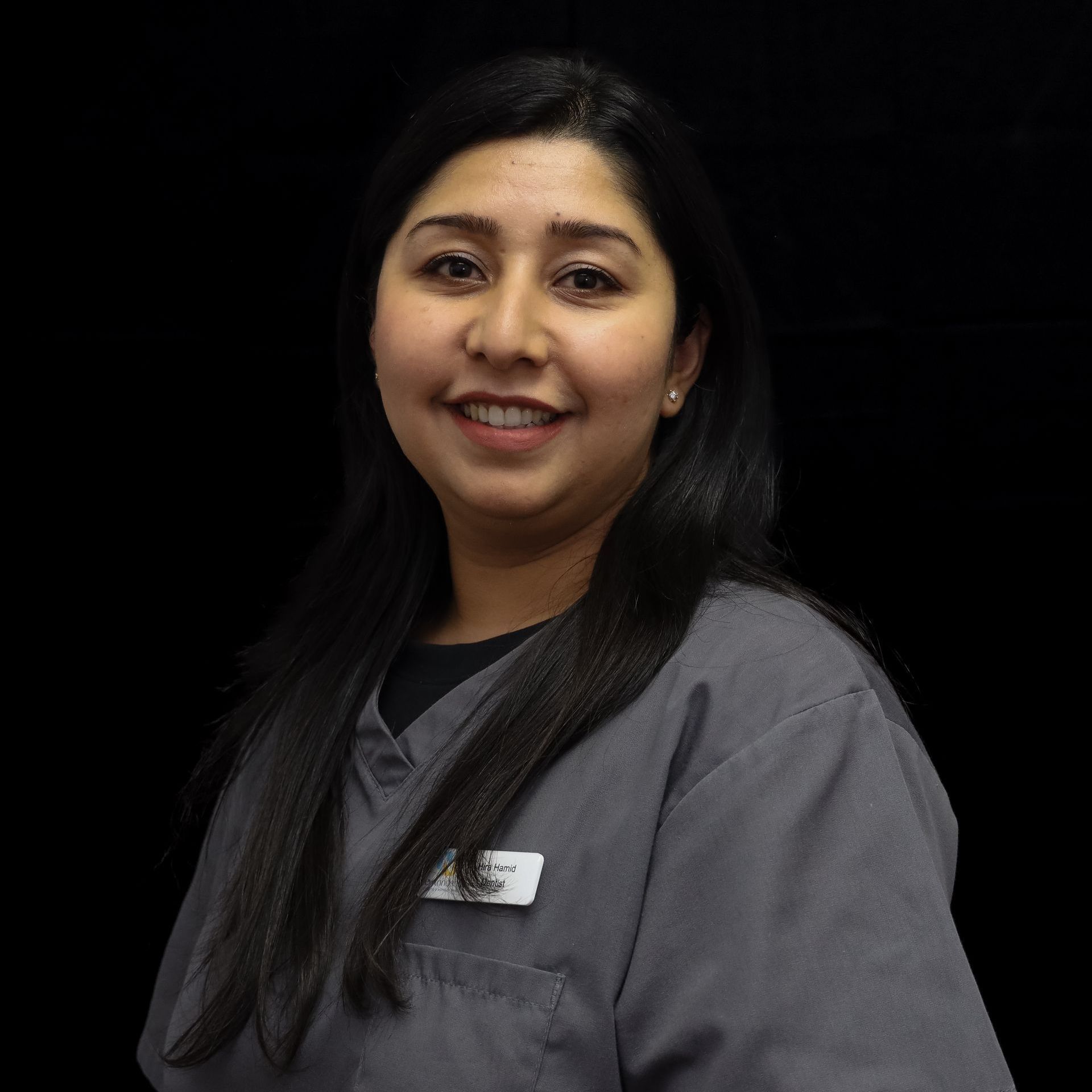 A woman in a grey scrub top is smiling for the camera.