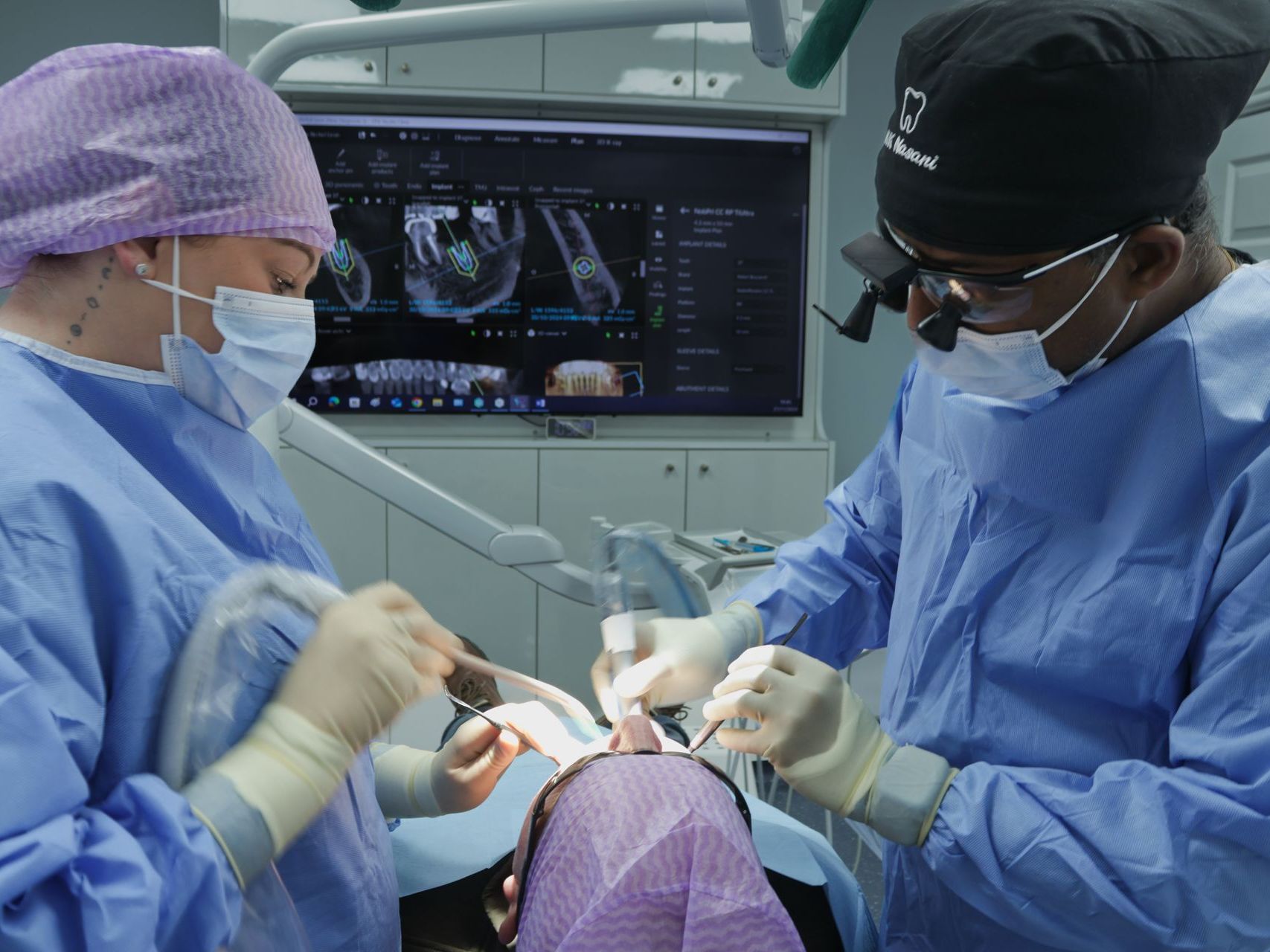 Two dentists are working on a patient in an operating room, carrying out 