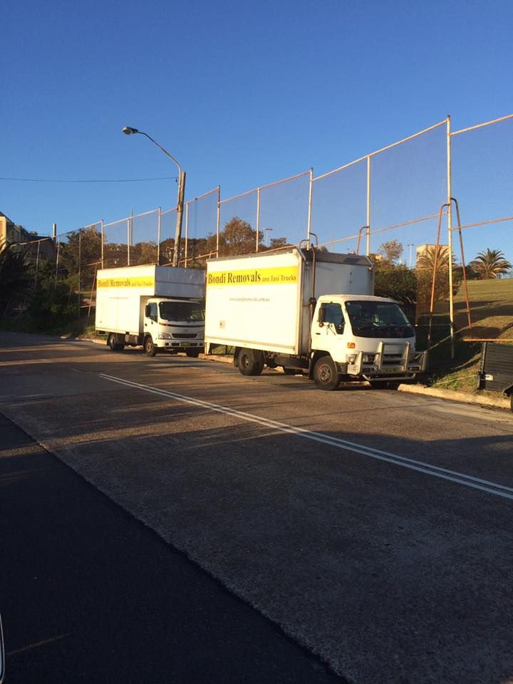 Two Moving Trucks Are Parked on The Side of The Road — Bondi Removals and Taxi Trucks in Sydney, NSW
