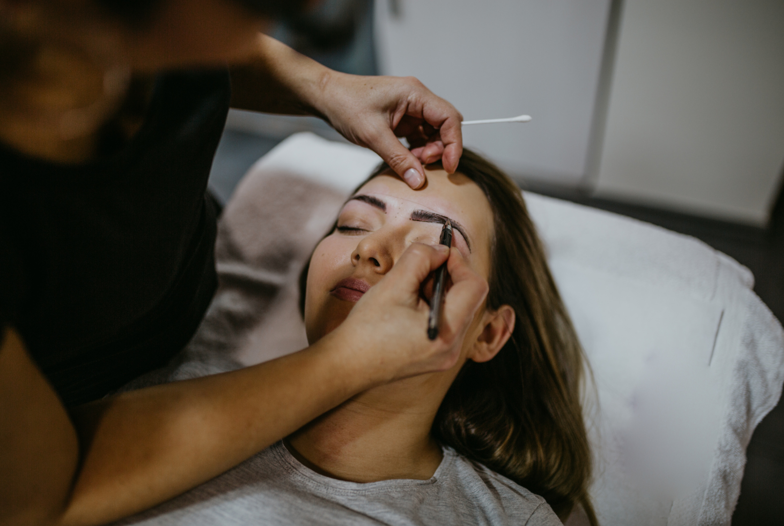 A woman is getting her eyebrows waxed in a salon.