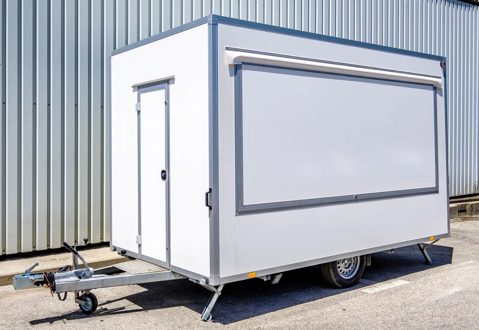 A white trailer is parked in front of a building.