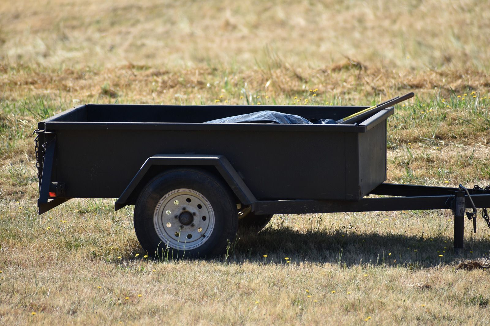 A small black trailer is parked in a grassy field.