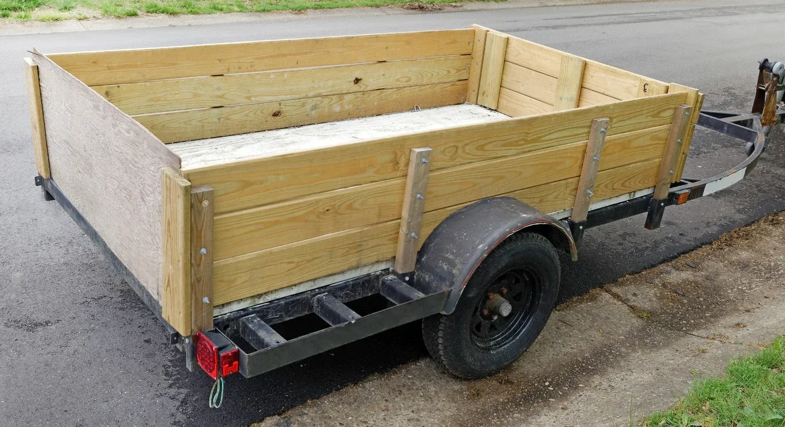 A small wooden trailer is parked on the side of the road.