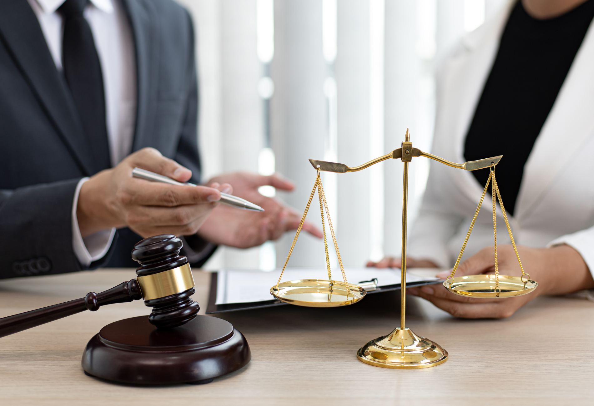 A man and a woman are sitting at a table with scales of justice and a gavel.