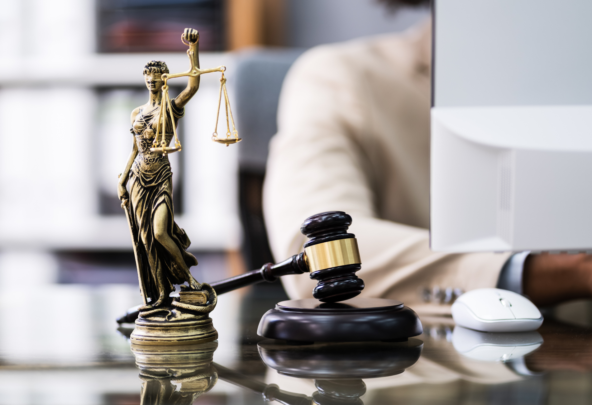 A statue of justice is sitting on a table next to a gavel.
