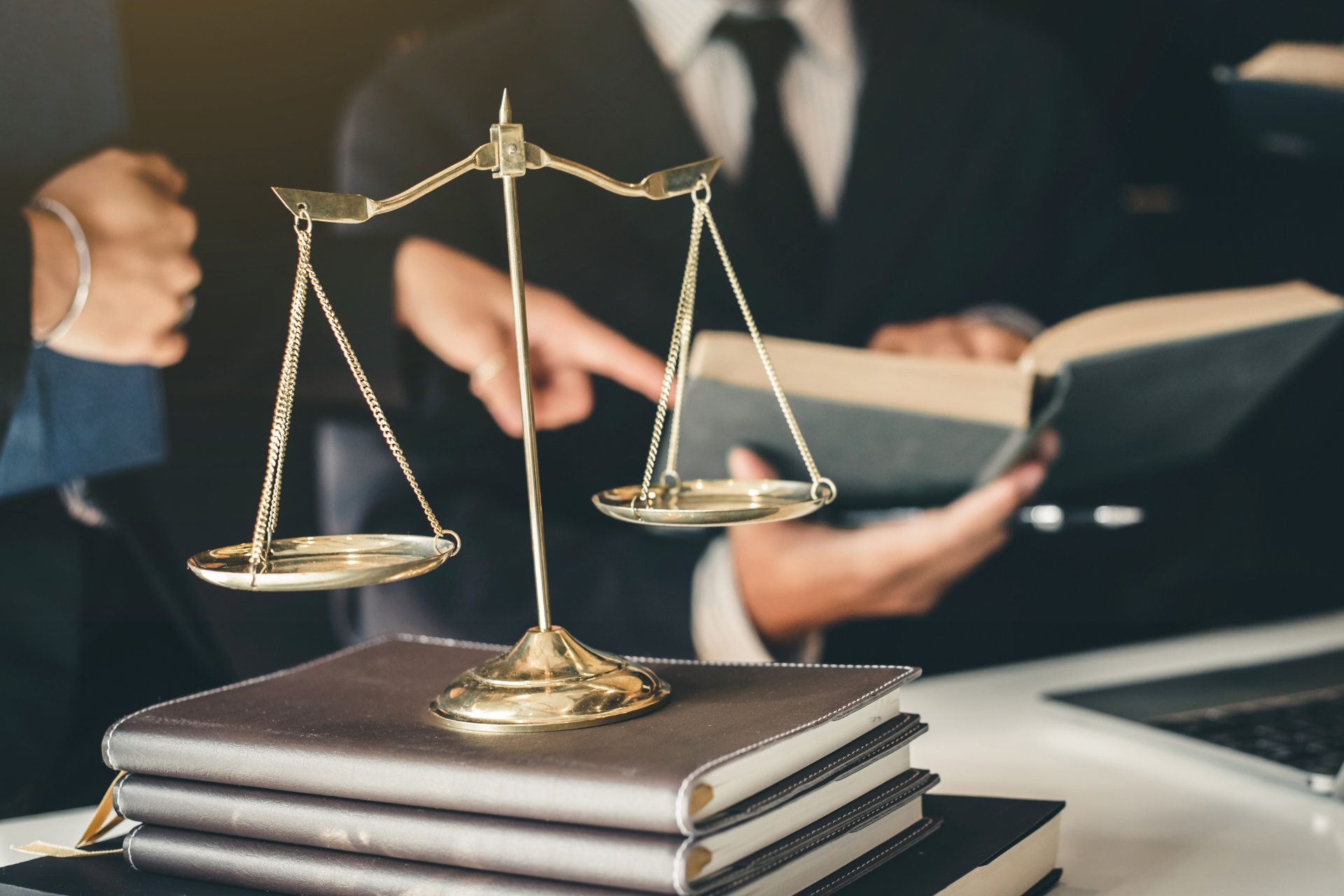 A group of lawyers are sitting at a table with a scale of justice and a book.