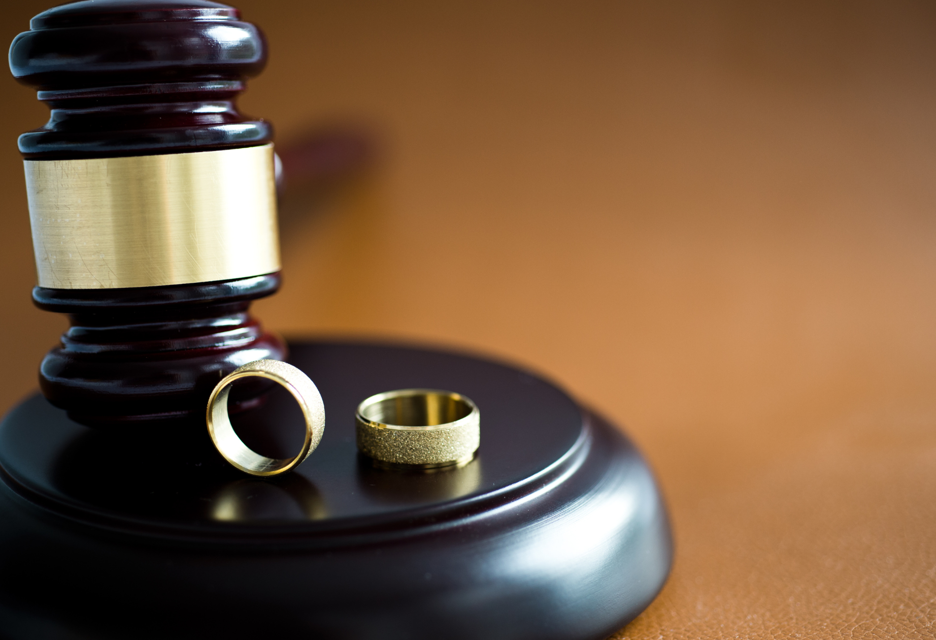 Two wedding rings are sitting on top of a wooden gavel.