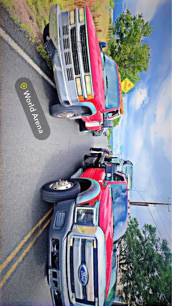 Red and silver Ford trucks parked on a road with yellow lines.