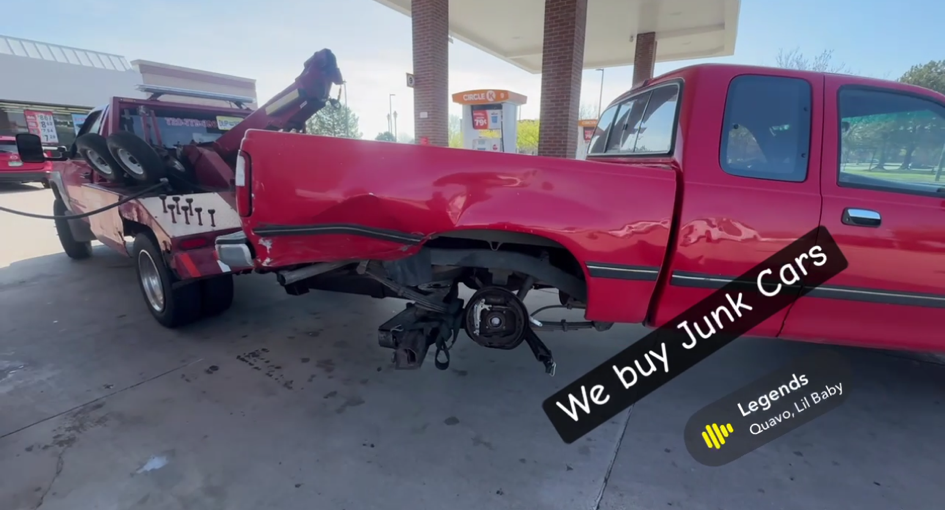 Red pickup truck damaged and being towed, with 