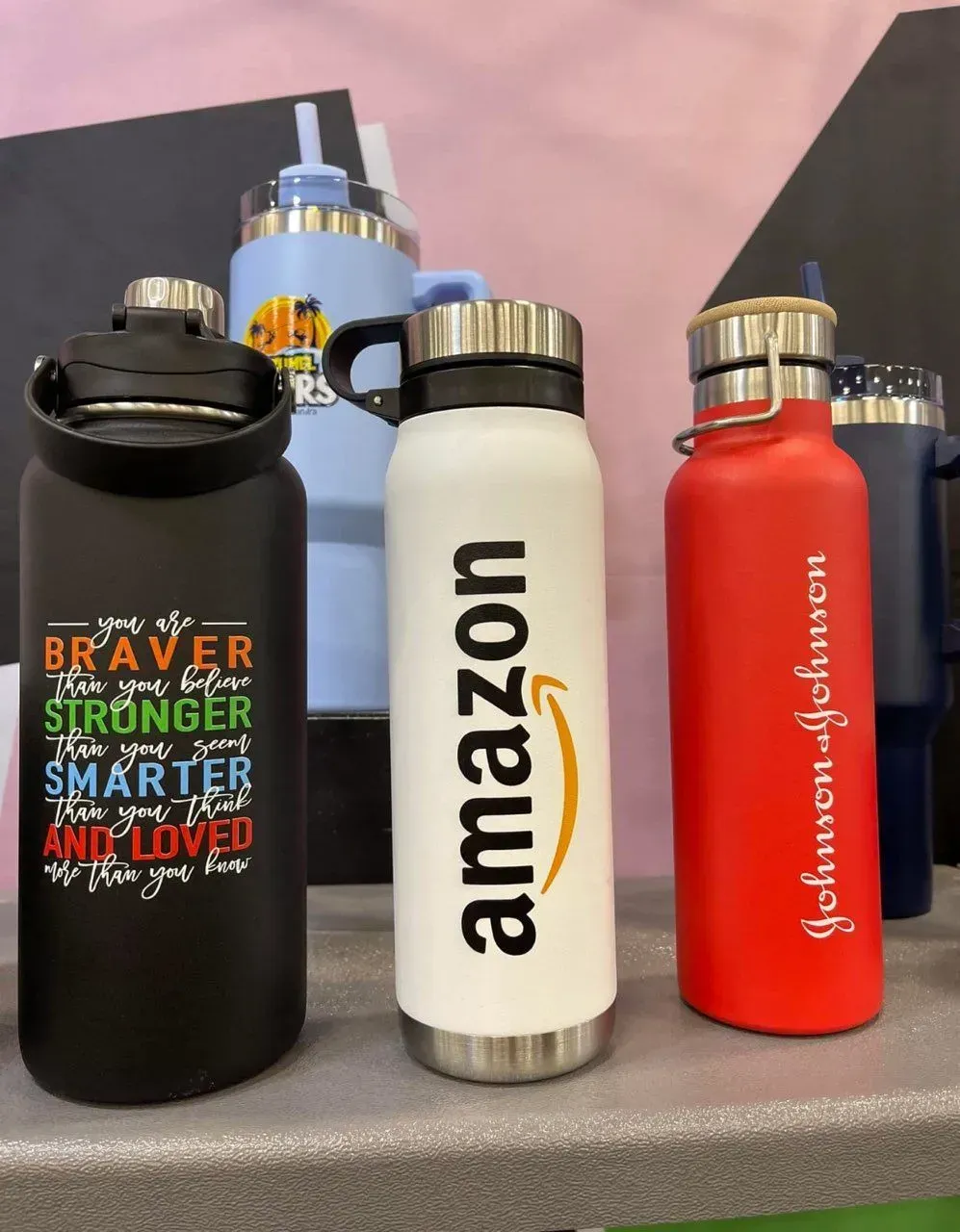 Water bottles with logos of Amazon and Johnson & Johnson; various colors, close-up.