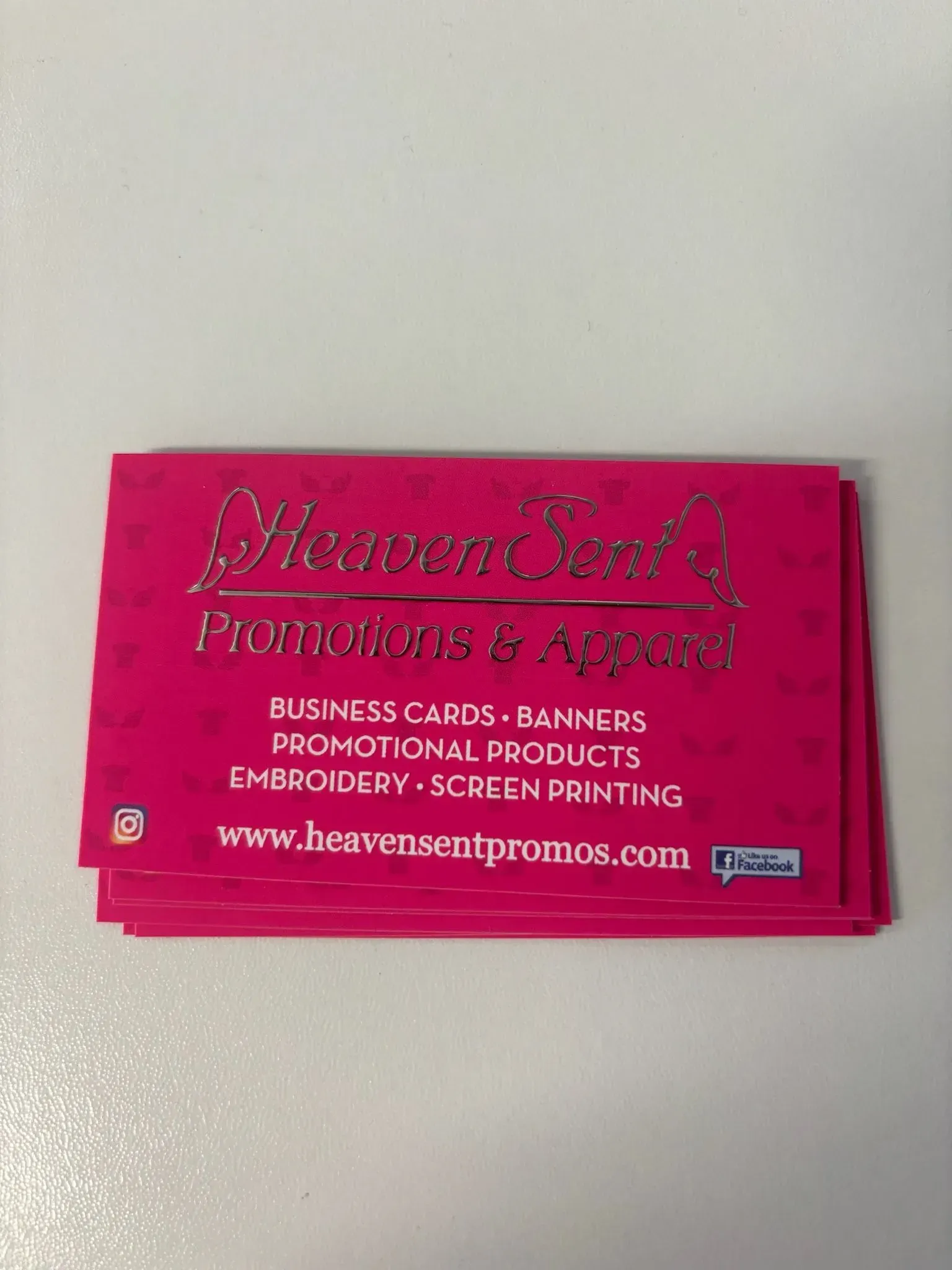 Pink business cards stacked, with silver text: