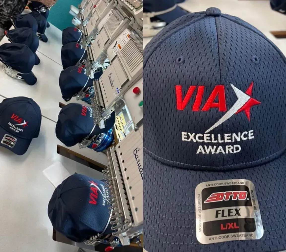 Embroidered blue VIA Excellence Award hats being made on a machine and a close-up of the hat.