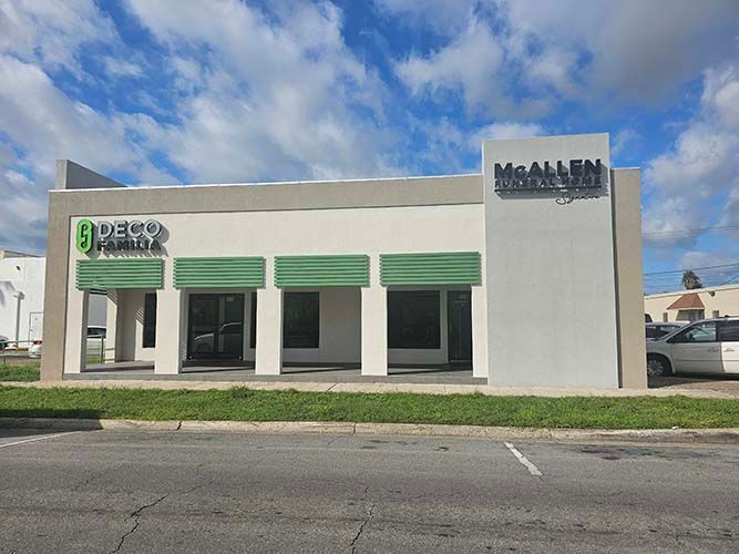 A white building with green awnings and a white van parked in front of it.