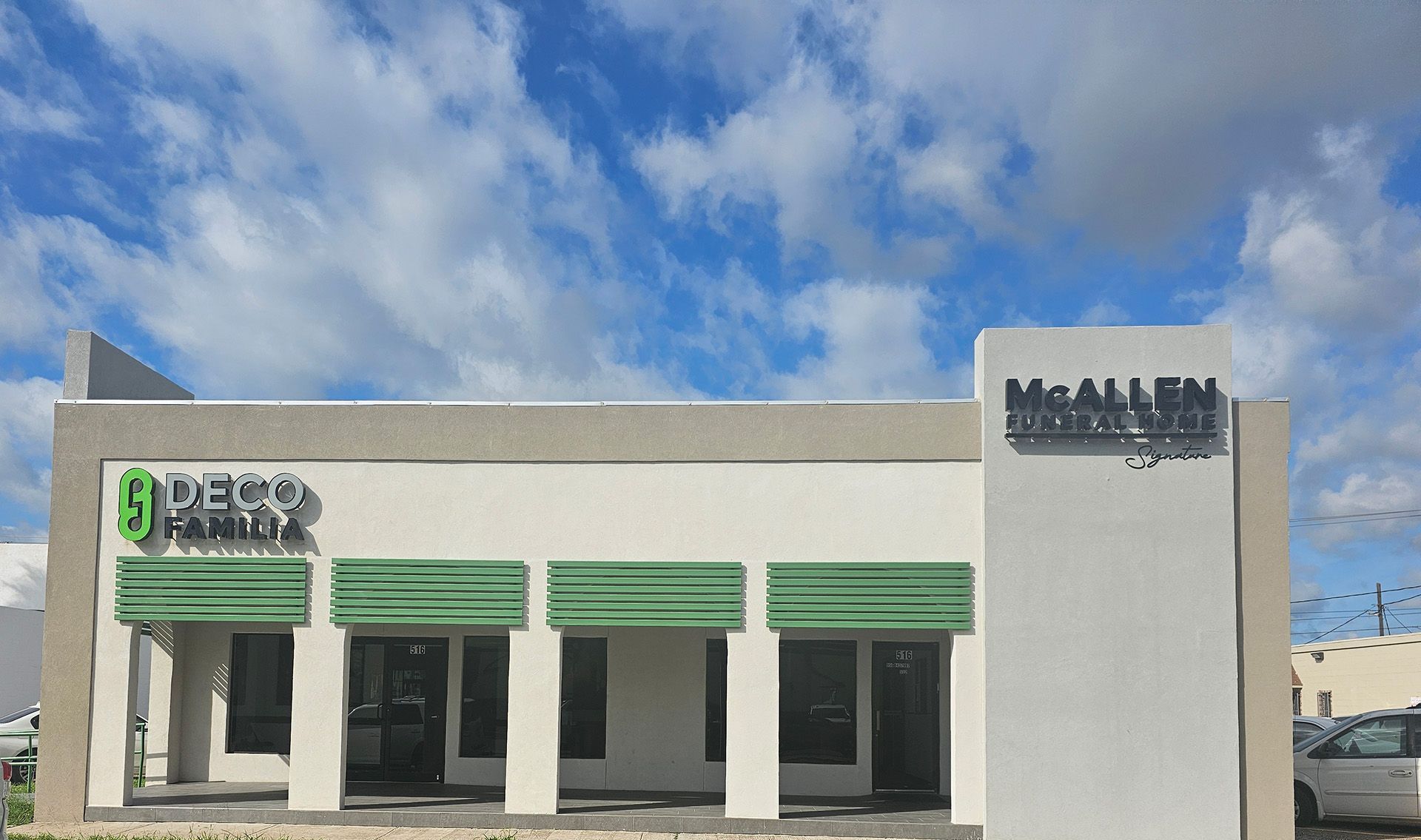 A white building with green awnings and a car parked in front of it.