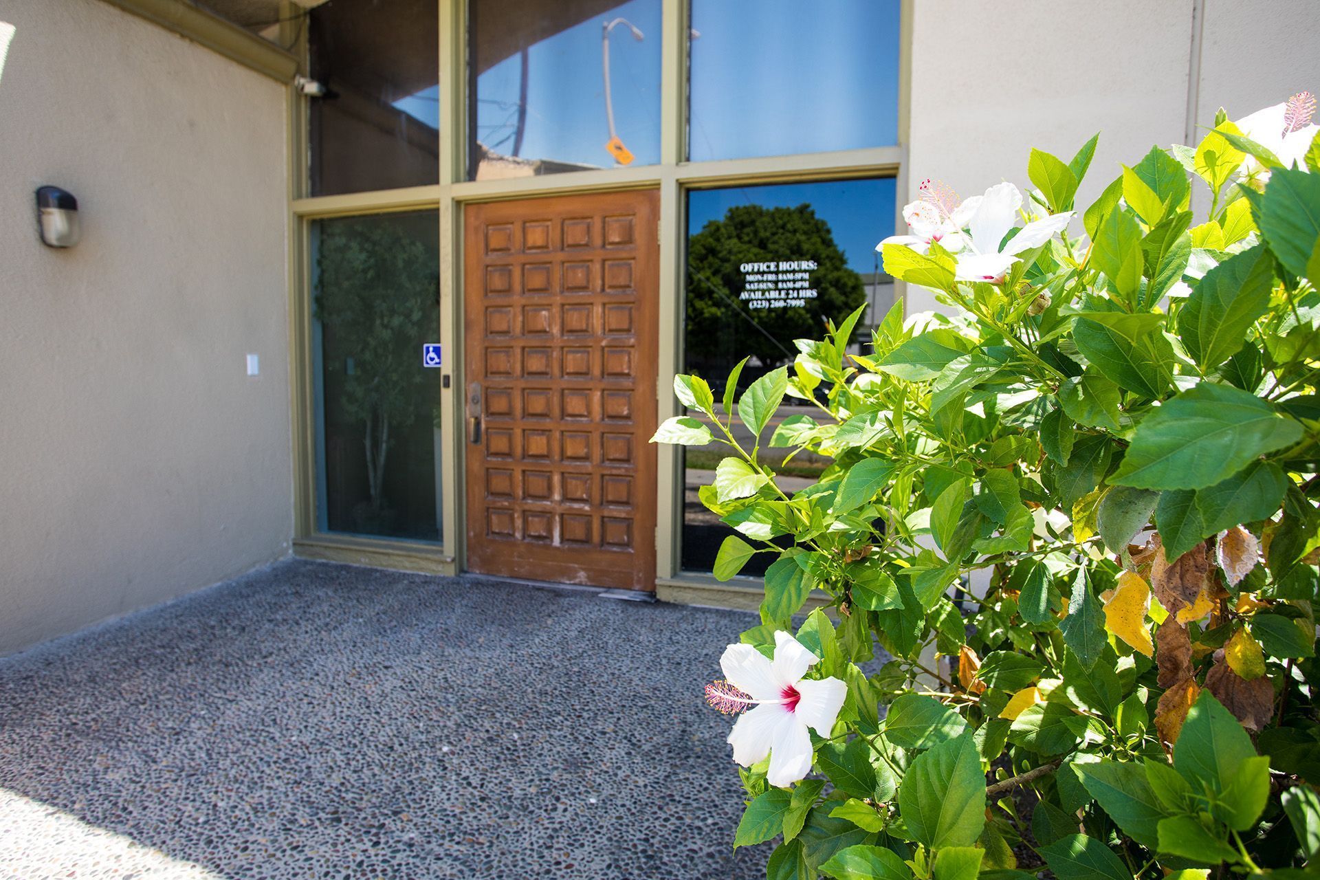 image of front door of east olympic funeral home with glass and a wooden door and flowers