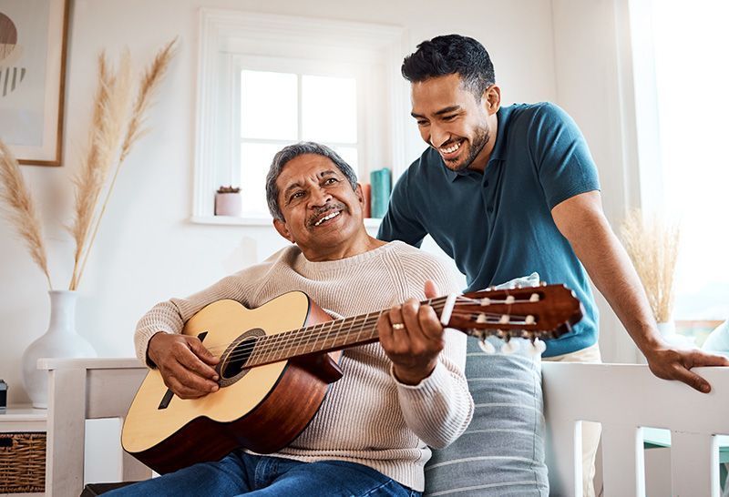A man is teaching an older woman how to play a guitar.