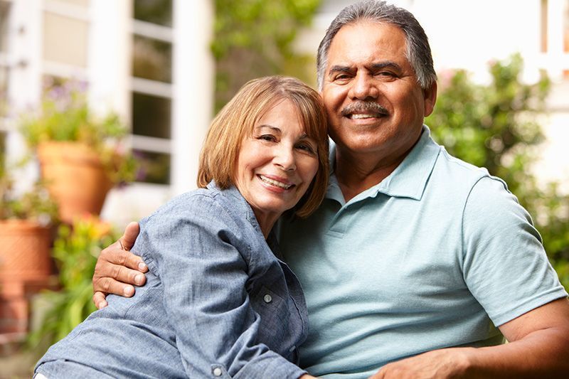 A man and a woman are sitting next to each other and smiling for the camera.