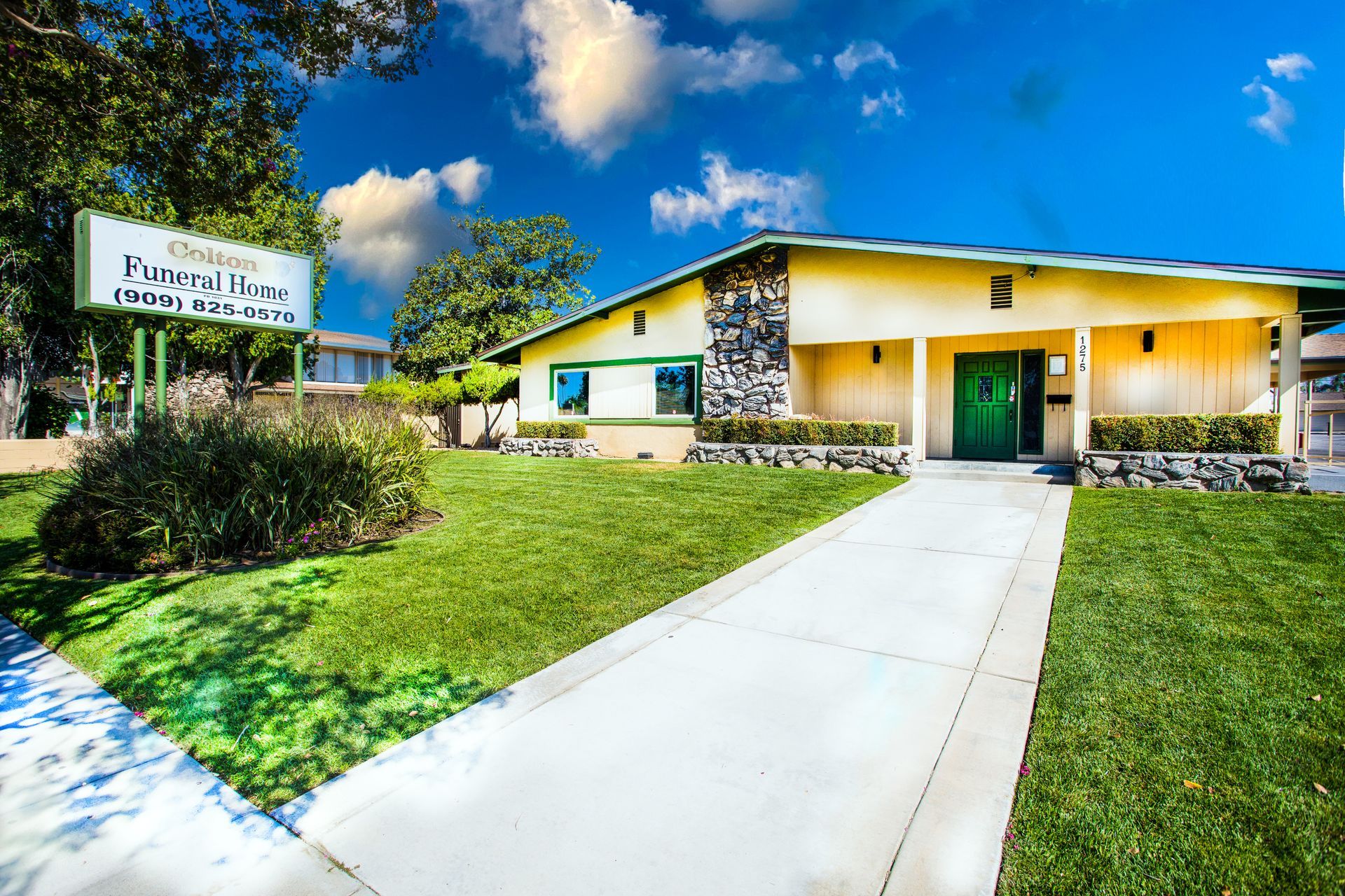 A yellow building with a green door and a sign that says ' funeral home ' on it