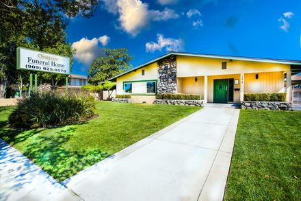 A yellow building with a green door and a sign that says ' funeral home ' on it