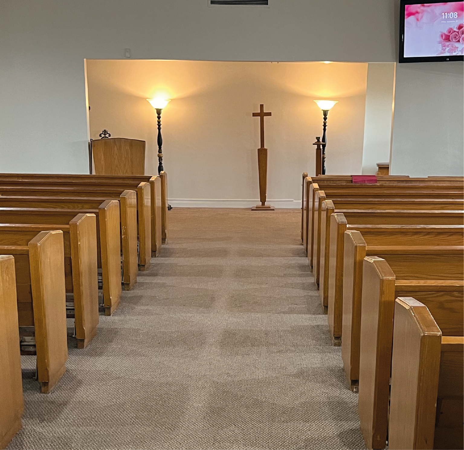 An empty church with rows of wooden benches and a coffin in the middle.