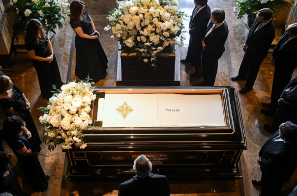 A group of people are standing around a coffin at a funeral.