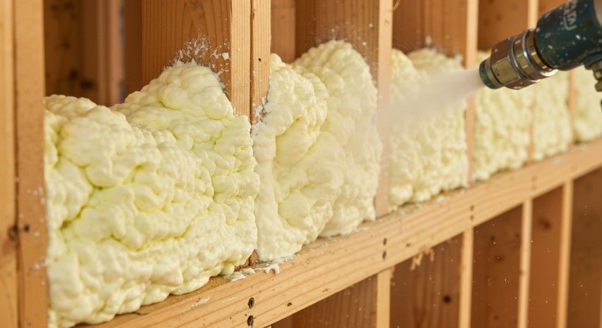 Spray foam insulation filling wall cavity between wooden studs