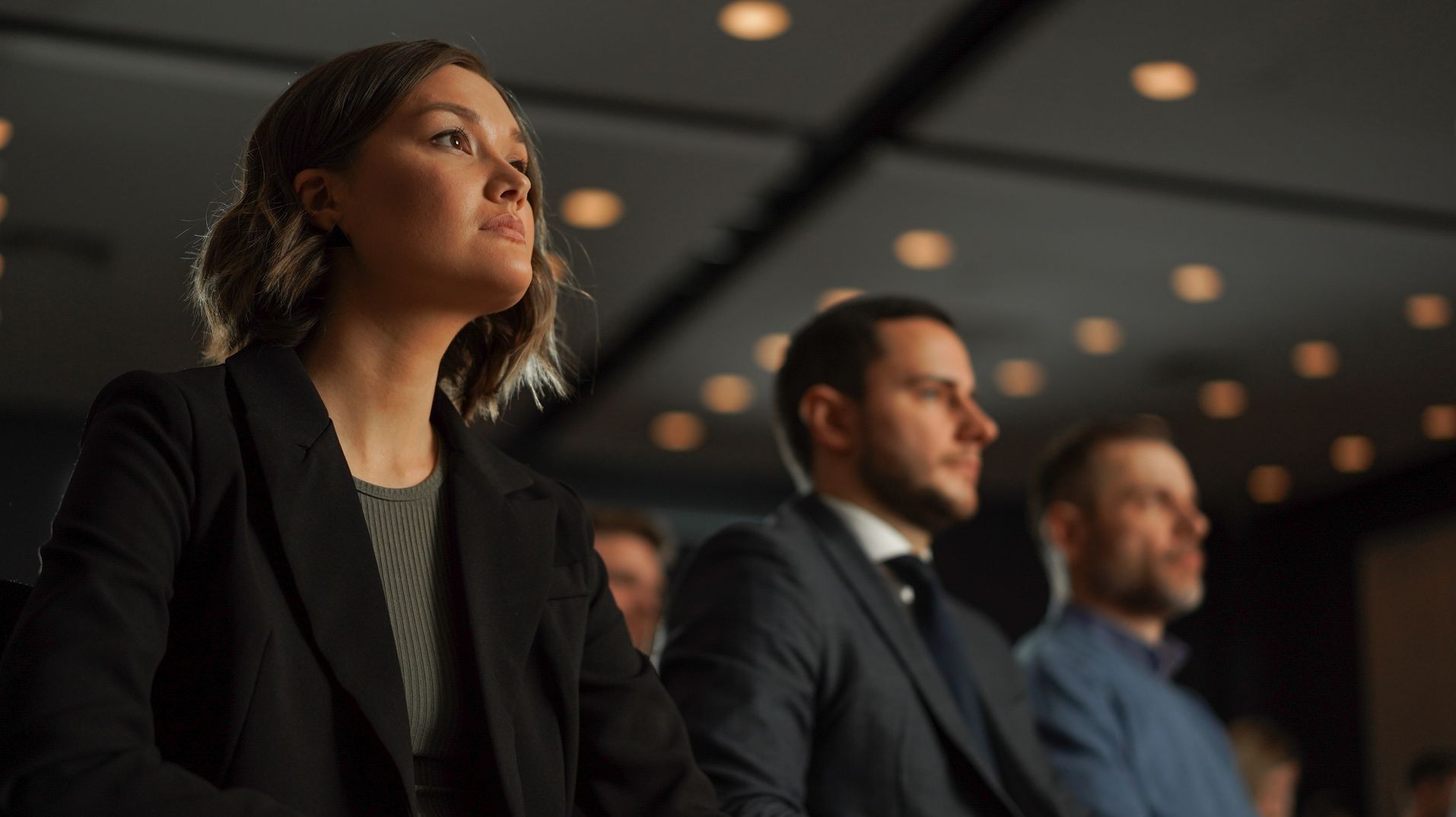 A group of people are sitting in a row at a conference.