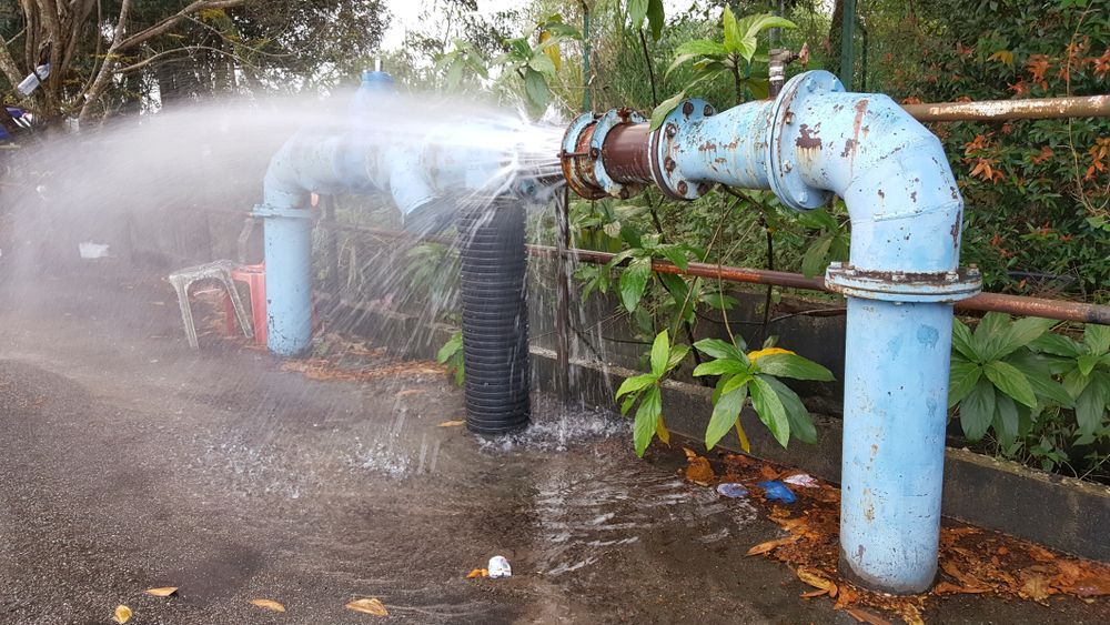 Water Spraying From a Broken Blue Pipe on a Walkway — Approved Plumbing Service in Woolner, NT