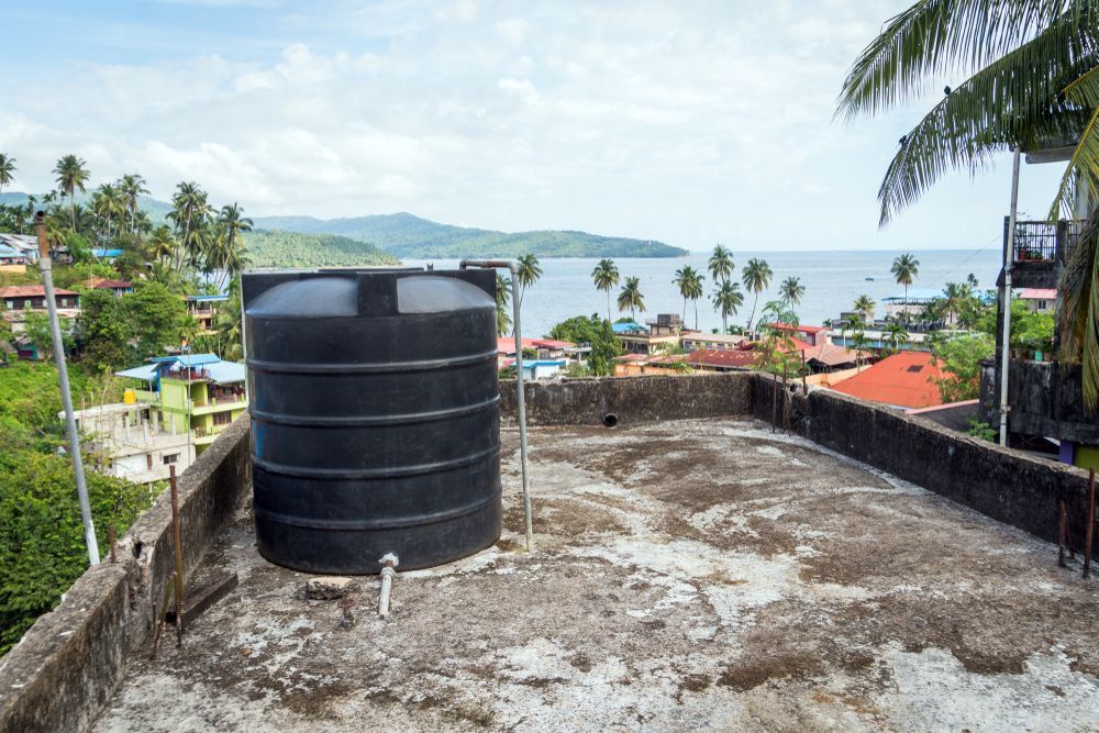 Black Water Tank on a Rooftop Overlooking a Coastal Town — Approved Plumbing Service in Woolner, NT