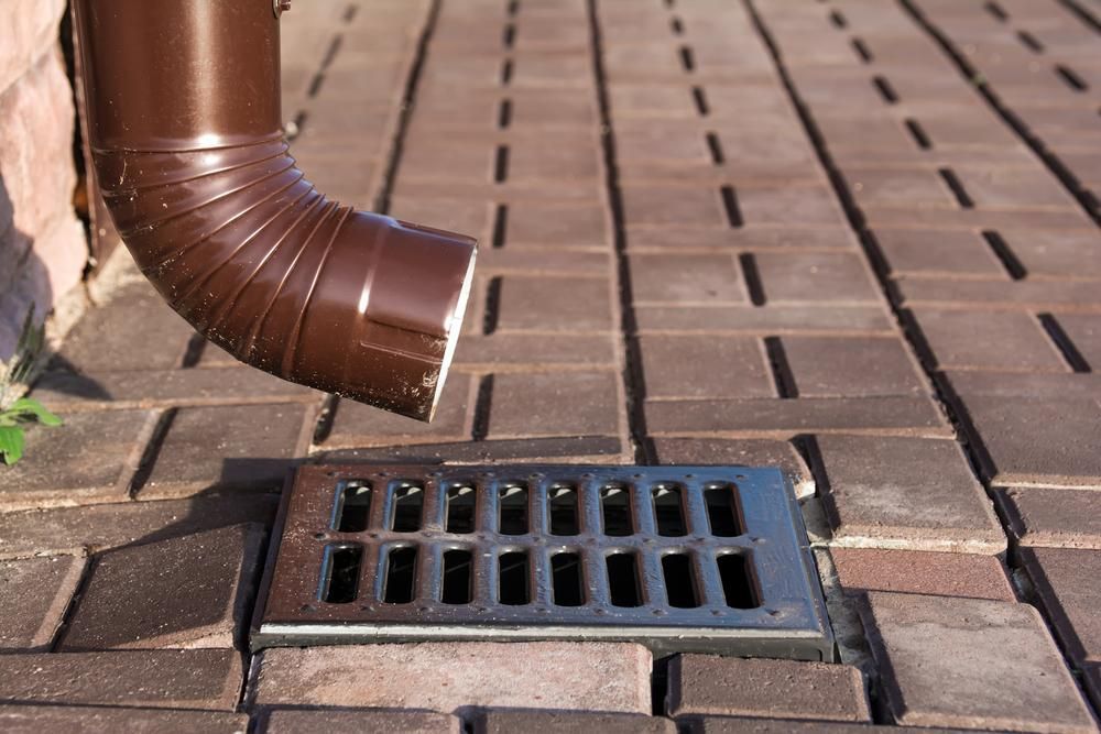 Brown Pipe is Coming Out of a Drain on a Brick Sidewalk — Approved Plumbing Service in Woolner, NT