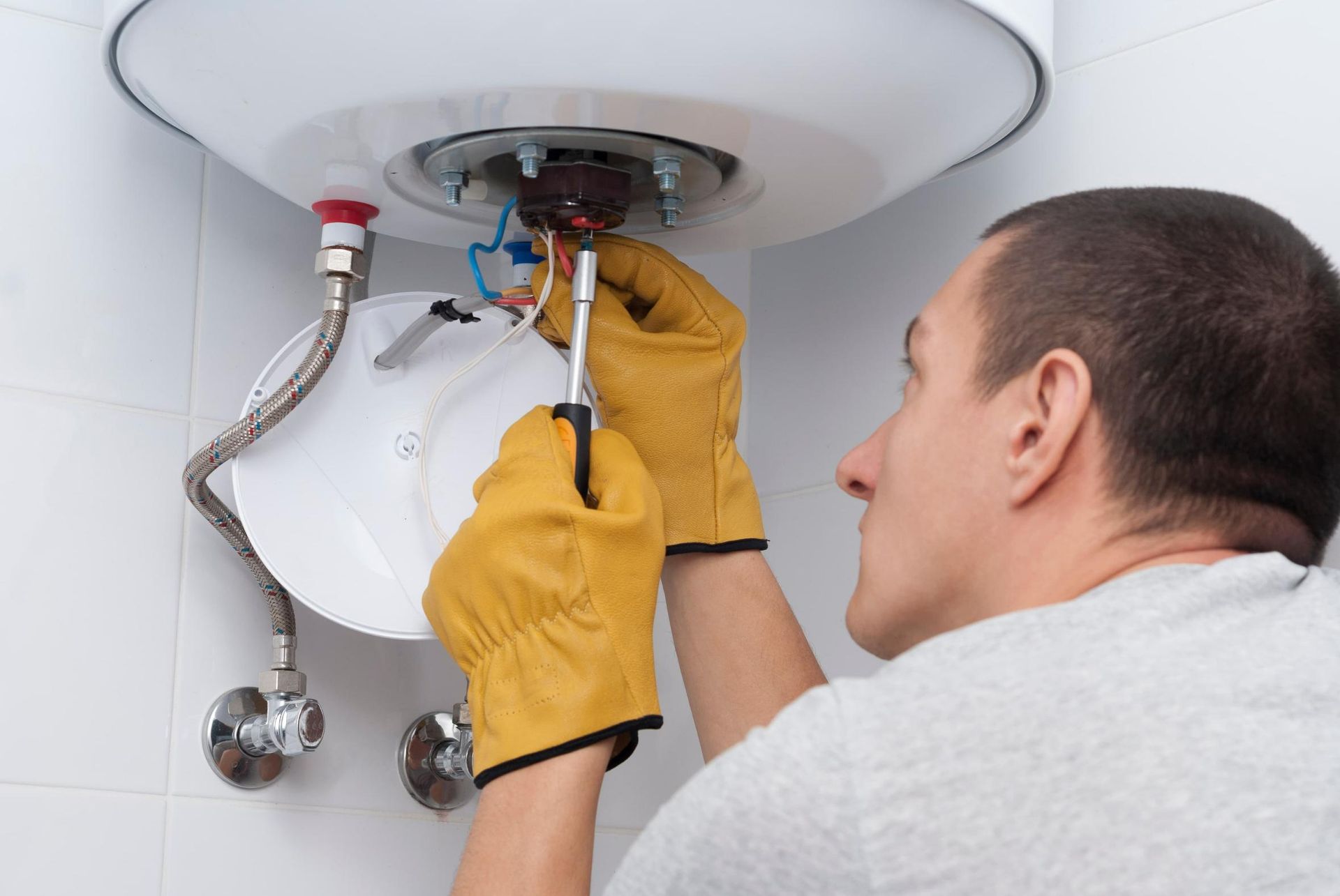 Man is Fixing a Water Heater With a Screwdriver — Approved Plumbing Service in Woolner, NT