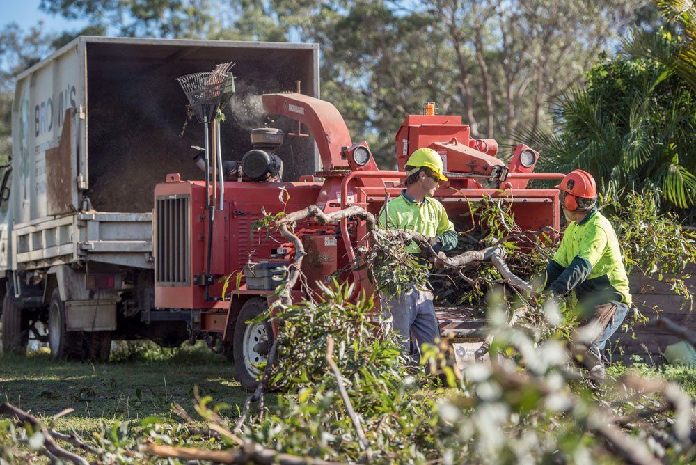 Two Men Are Working On A Tree Chipper In Front Of A Truck — Brown's Professional Tree Service In Pie Creek, QLD