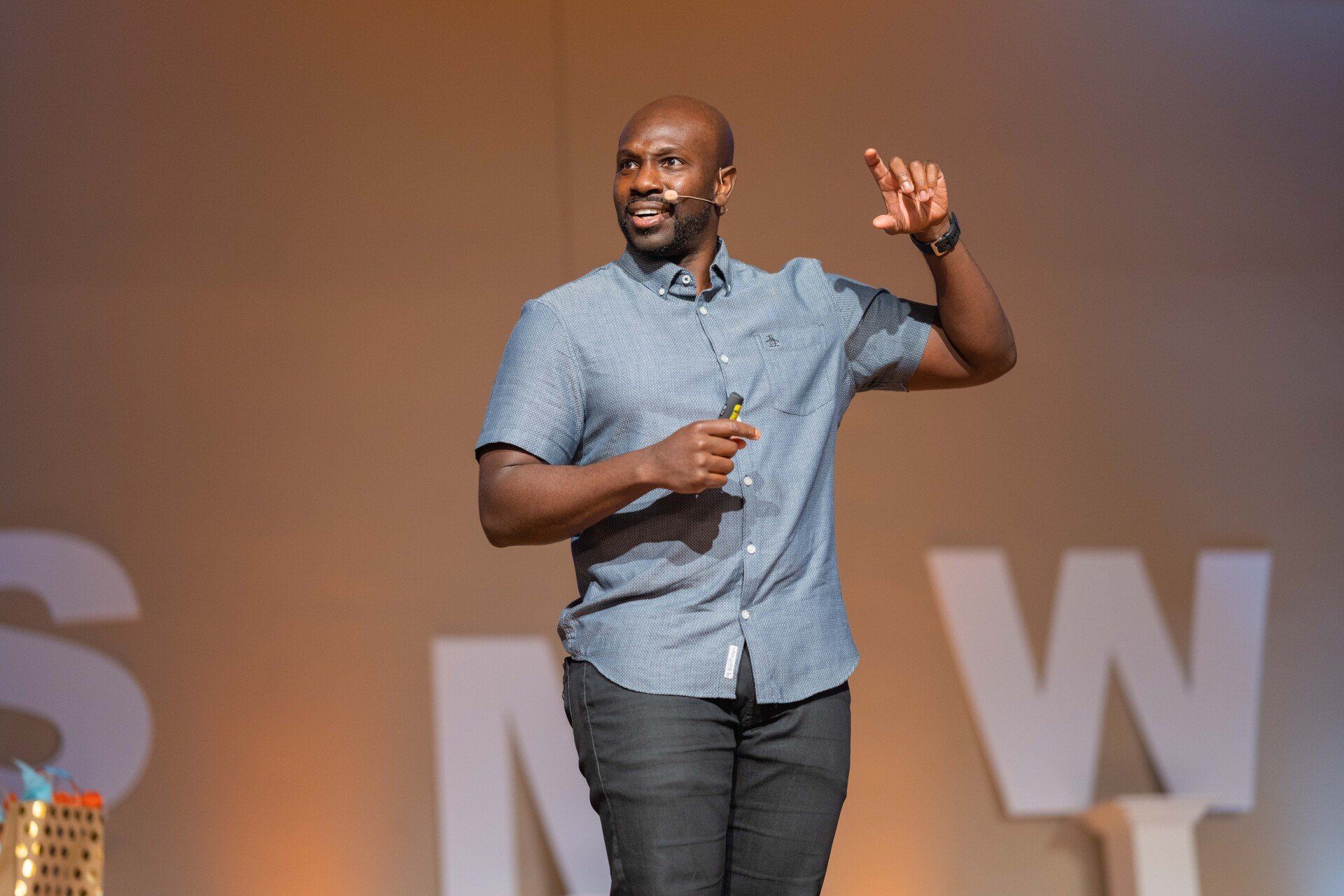 A Juntae Delane is standing on a stage, holding a microphone, and giving a speech.
