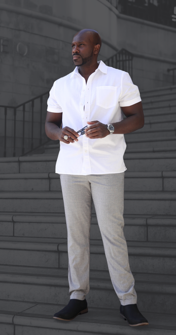 A Juntae Delane in a white shirt and grey pants is standing on a set of stairs.