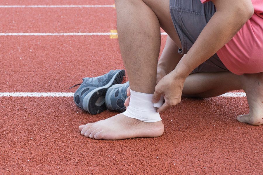 A Person Is Bandaging Their Ankle on A Track — Align Health Therapies in Bulli, NSW