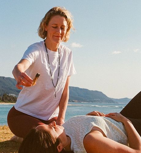A Woman is Kneeling Down Next to a Woman Laying on the Ground — Align Health Therapies in Woonona, NSW