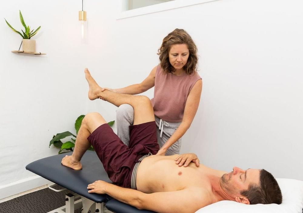 A Woman is Examining a Man's Leg on a Table — Align Health Therapies in Woonona, NSW