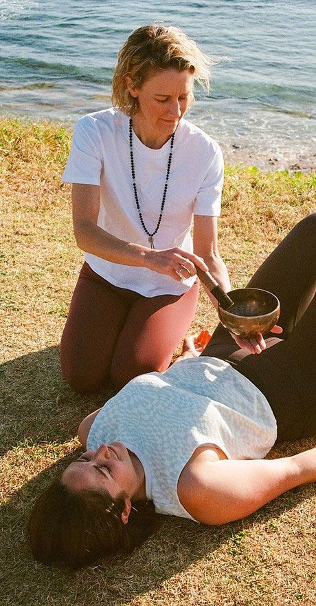A Woman is Kneeling Down Next to a Woman Laying on the Ground — Align Health Therapies in Woonona, NSW
