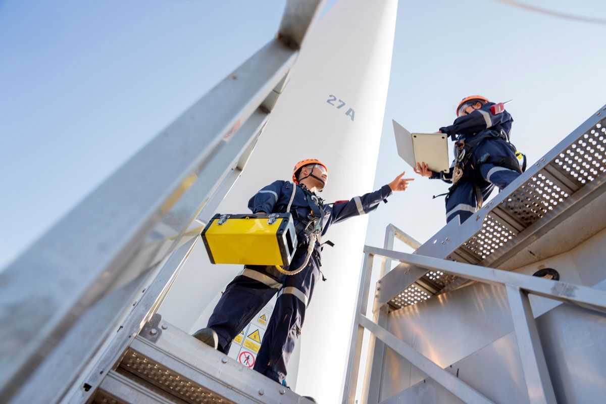 Two men are standing on a ladder next to a rocket.