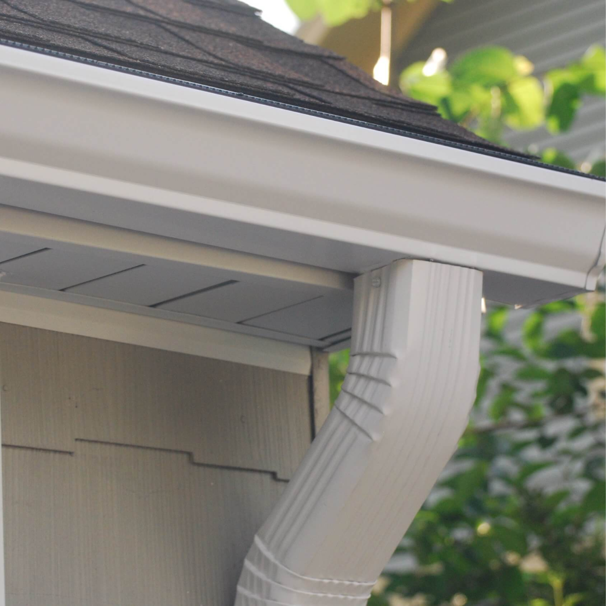 Gray gutters on a house, with a downspout. The roof and siding are visible.