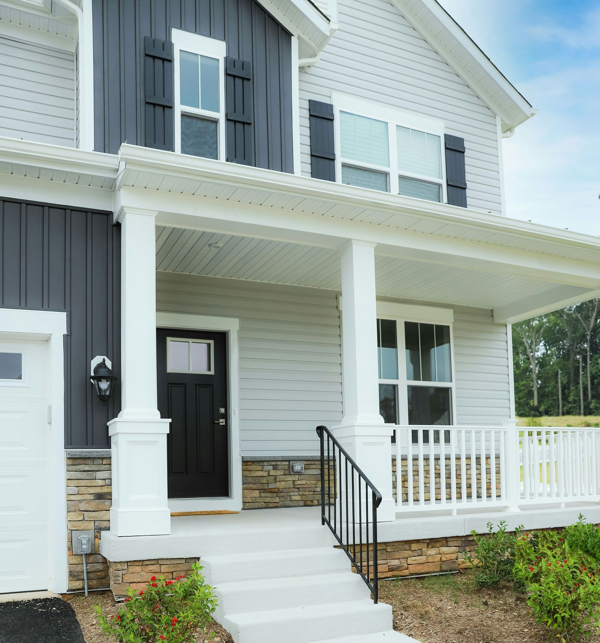 Two-story house with gray siding, dark blue accents, white porch, black door.
